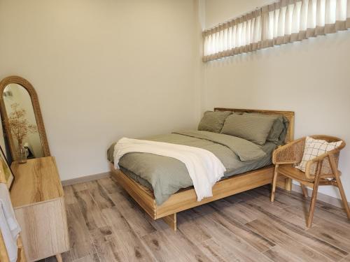 Łóżko w pokoju z lustrem i krzesłem w obiekcie Self house (Cozy private house) w mieście Hat Yai