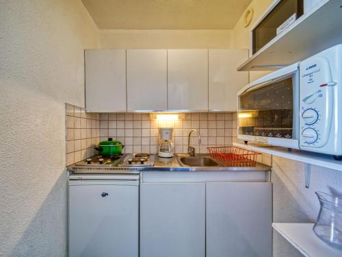 une cuisine avec des armoires blanches, un évier et un micro-ondes dans l'établissement Apartment Lunik Orion-41 by Interhome, au Corbier