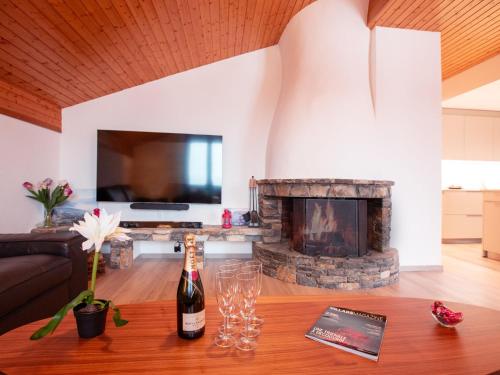 a living room with a fireplace and a bottle of wine on a table at Apartment Grand-Pont 15 by Interhome in Villars-sur-Ollon