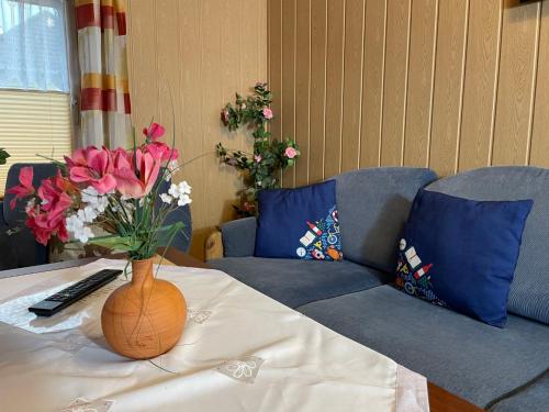 eine Vase mit Blumen auf einem Tisch mit einer Couch in der Unterkunft Apartment Old Hüsung - MUZ327 by Interhome in Mirow