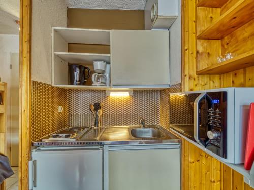une petite cuisine avec un évier et un micro-ondes dans l'établissement Studio Asters 18 Bâtiment C1 by Interhome, aux Menuires