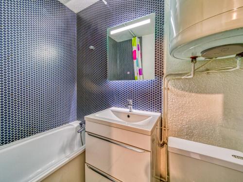 une salle de bain avec un lavabo, une baignoire et un miroir dans l'établissement Studio Asters 18 Bâtiment C1 by Interhome, aux Menuires