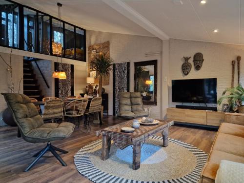 a living room with a television and a table and chairs at Boutique Bungalow 2 met sauna, hottub en boskas in Rheezerveen