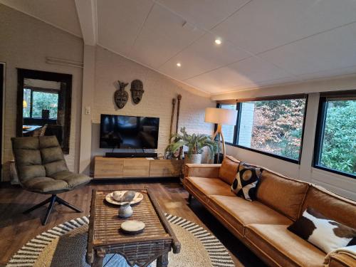 a living room with a couch and a table at Boutique Bungalow 2 met sauna, hottub en boskas in Rheezerveen