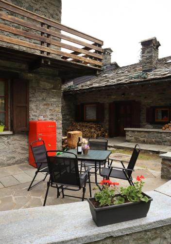 a patio with a table and chairs in front of a building at Maison Chez Les Roset in Arvier