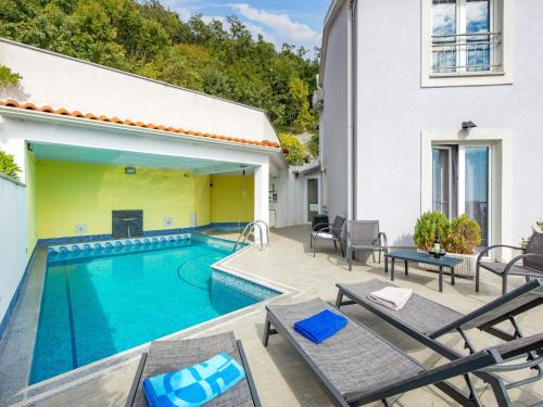 een zwembad naast een huis met stoelen bij Apartment Bella Vista - OPA104 by Interhome in Jurdani