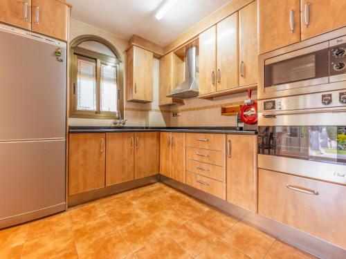 a kitchen with wooden cabinets and stainless steel appliances at Holiday Home Villa Jardin by Interhome in Vilafortuny