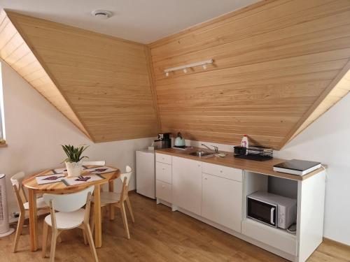 a kitchen with a wooden ceiling and a table with chairs at Apartament Grel in Nowy Targ