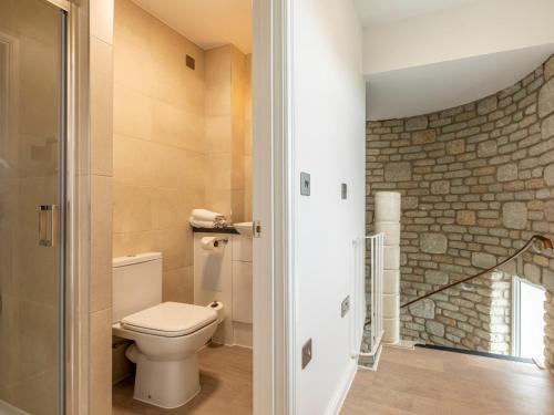 a bathroom with a toilet and a stone wall at 2 Bed in St. Mellion 87703 in St. Mellion