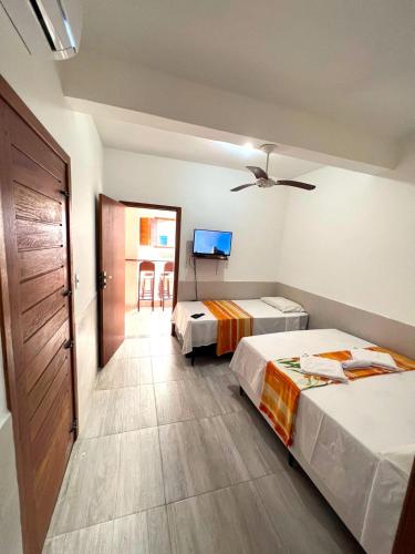 a hotel room with two beds and a tv at Hospedaria Mucugê - na principal rua da cidade, Rua do Mucugê - Arraial d'Ajuda in Arraial d'Ajuda