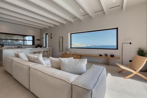 a living room with a white couch and a large screen at Apollo Yard Villa in Mikonos