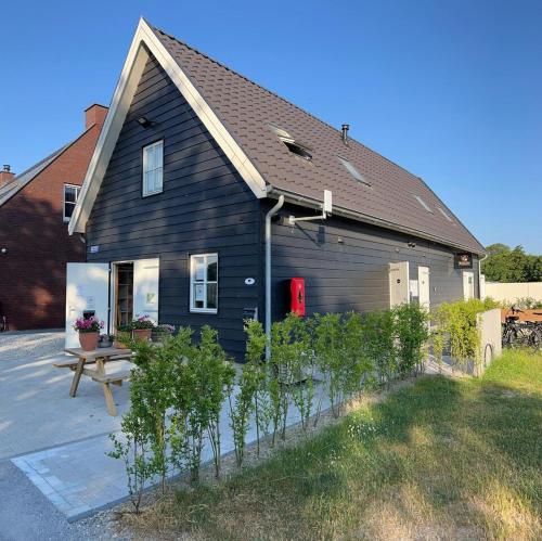 a black house with a bench in front of it at B&B Studio/Appartement Bij Zee in Stellendam