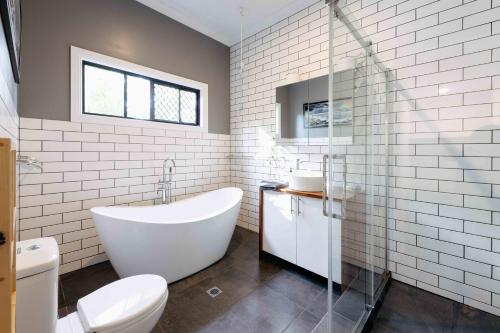 a white bathroom with a tub and a toilet at kin kin cottage, Noosa hinterland, walk to town. in Kin Kin
