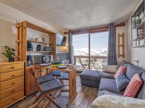 a living room with a table and a couch and a desk at Studio Soyouz Vanguard-100 by Interhome in Le Corbier