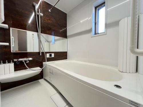 a white bathroom with a tub and a sink at Charming New Home Launch: Direct access to Narita & Haneda Airports, Shinjuku, and Disneyland; Close to Asakusa & Akihabara! in Tokyo