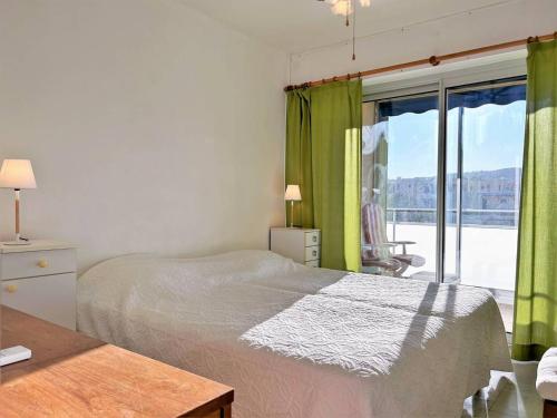 - une chambre avec un lit et une fenêtre avec des rideaux verts dans l'établissement Appartement à 150m de la plage avec terrasse fermée et parking privatif - Bormes-les-Mimosas - FR-1-251-578, à Bormes-les-Mimosas