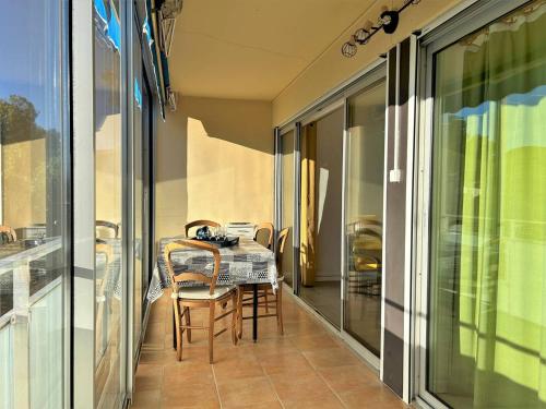 une salle à manger avec une table et des chaises sur un balcon dans l'établissement Appartement à 150m de la plage avec terrasse fermée et parking privatif - Bormes-les-Mimosas - FR-1-251-578, à Bormes-les-Mimosas