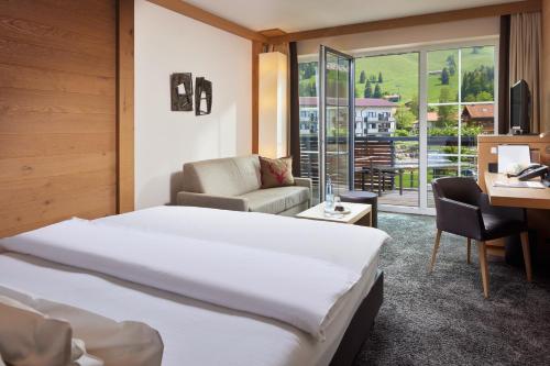 a hotel room with a large bed and a desk at Panoramahotel Oberjoch in Bad Hindelang