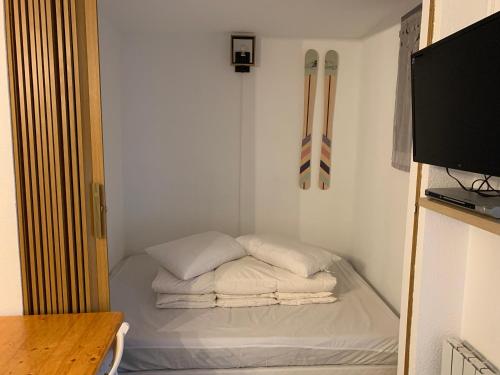 ein kleines Zimmer mit einem Bett und Skiern an der Wand in der Unterkunft La Foux d’Allos, centre station proche pistes in Allos