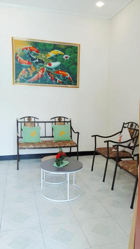 a room with two benches and a table and a painting at Penginapan Prambanan TRISAN in Randugunting
