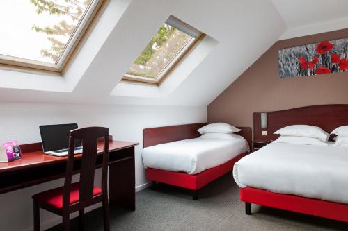 sypialnia z 2 łóżkami i biurkiem z laptopem w obiekcie Hôtel Arras Sud w mieście Arras
