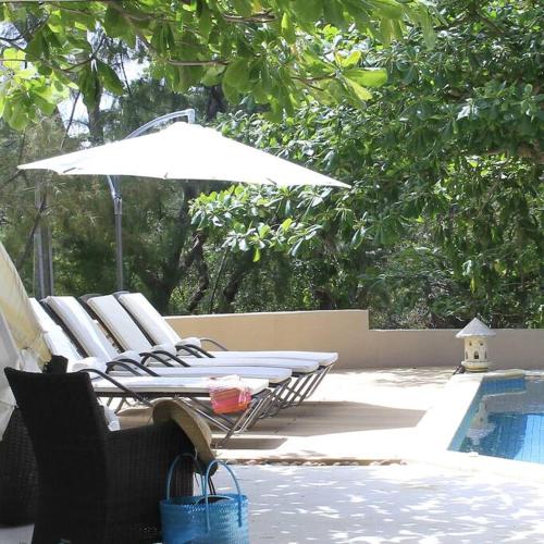 a group of chairs and an umbrella next to a pool at Villa Fayette Sur Mer in Post of Flacq
