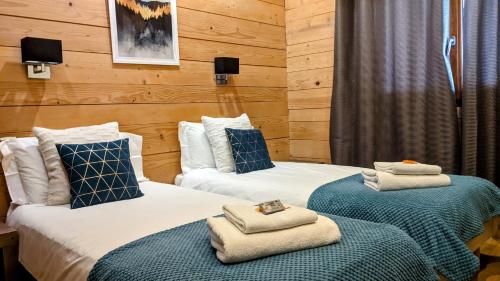 two beds in a hotel room with towels on them at Chalet Robin - spa- multipass- terrain de pétanque in Morzine