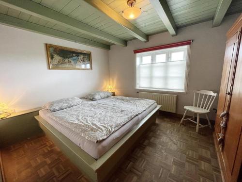 een slaapkamer met een bed, een raam en een stoel bij Das Puppenhaus, Reetdach, Sauna, Kamin, eingezäunt, Badewanne, Haustiere willkommen in Emmelsbüll-Horsbüll
