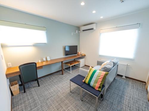 a living room with a couch and a desk and a television at AIR FURANO in Furano