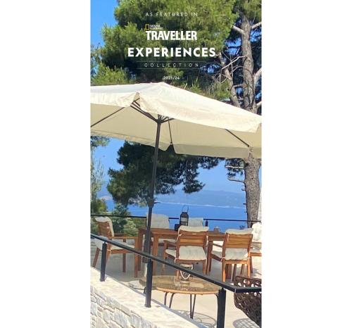 a table and chairs under a white umbrella at Damari Luxury Retreat Villas Skiathos in Skiathos Town