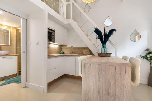 d'une cuisine avec des placards blancs et une table avec une plante. dans l'établissement Appartement Pinède, au Cap d'Agde