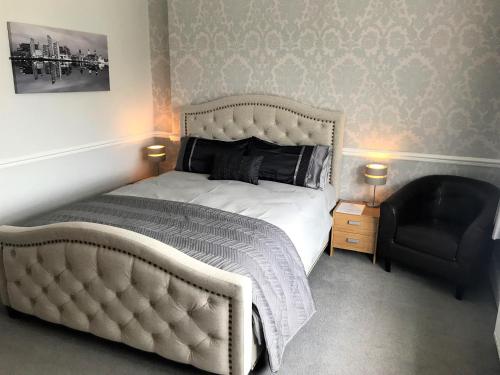 a bedroom with a white bed and a black chair at Orrell Park Hotel in Liverpool
