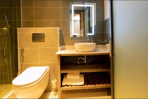 Un baño con lavabo, inodoro y espejo. en BISABO SUITES APARTMENT LTD, en Kigali