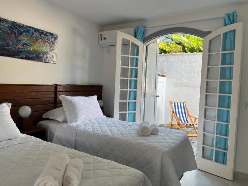 a bedroom with two beds and a sliding glass door at Casa Arte Cabore in Paraty