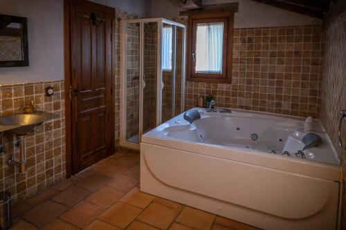 baño con bañera grande y lavamanos en Posada Restaurante Fuenteplateada en Collado Hermoso