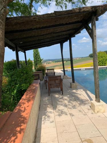 a wooden pergola with two benches next to a pool at Les 5 terrasses - vue imprenable et piscine privée in La Sauvetat