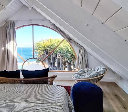 a bedroom with two beds and a large window at The Dragon Tree Guesthouse in Kalk Bay