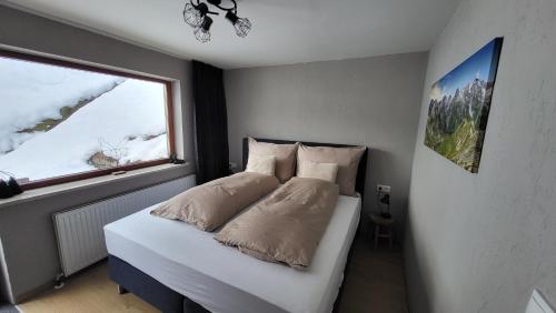 a bedroom with a white bed with a window at Haus Grübl in Wald im Pinzgau