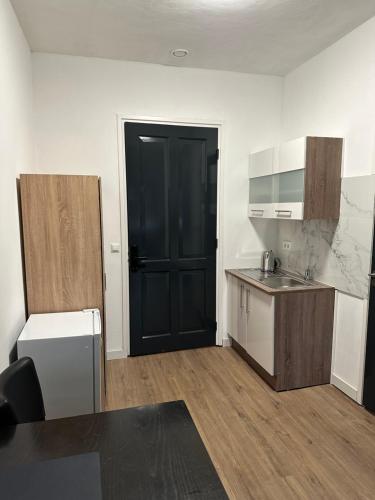 uma cozinha vazia com uma porta preta num quarto em B&B Santorini em Maasbree