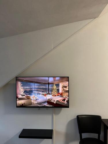 TV de pantalla plana colgada en la pared en B&B Santorini, en Maasbree
