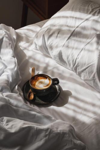 a cup of cappuccino on a bed with a plate of food at Casa Maca in Ibiza Town