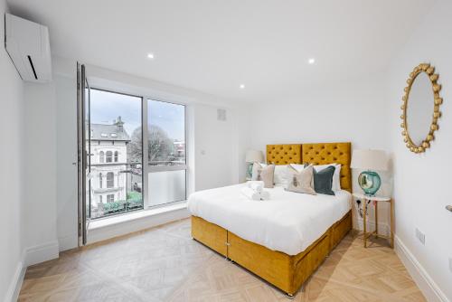 a white bedroom with a large bed and a window at Flat 205 in London