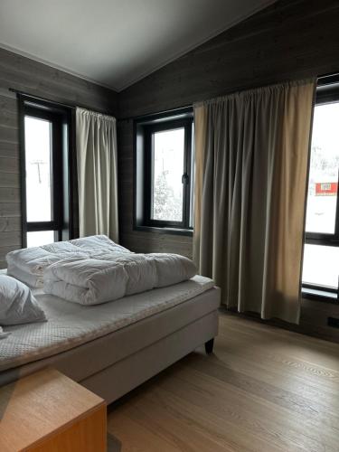 1 dormitorio con 1 cama grande y ventanas en Luksus i Riddergaarden, en Beitostølen