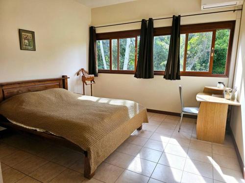 1 dormitorio con 1 cama, escritorio y ventanas en Maison en bois au Mont mou, en Païta