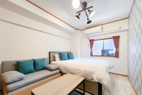 a bedroom with a bed and a couch at Alita Mansion Kyobashi in Osaka