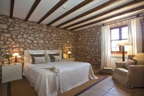 a bedroom with a large bed and a stone wall at Agroturisme Son Cardaix in Artá