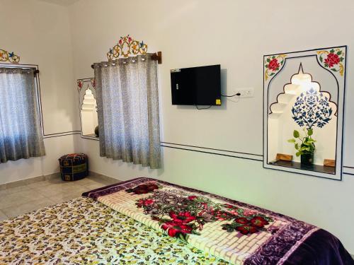 Hotel tulsi palace في بوشكار: غرفة نوم مع سرير وتلفزيون على الحائط