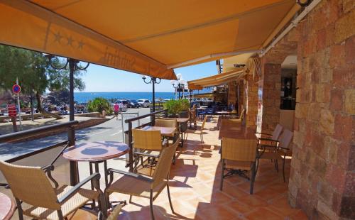 un patio esterno con tavoli, sedie e vista sull'oceano di Hôtel & Résidence Le Subrini a Porto Ota