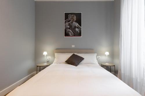 a bedroom with a large white bed with two lamps at River61 - Guest House in Rome