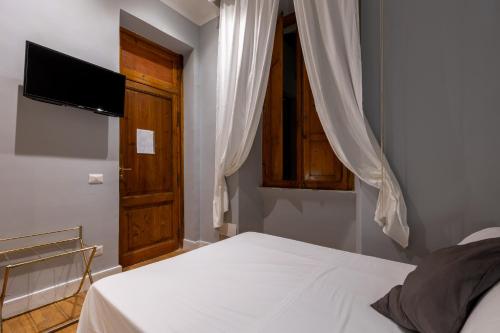 a bedroom with a bed with a tv and a window at River61 - Guest House in Rome